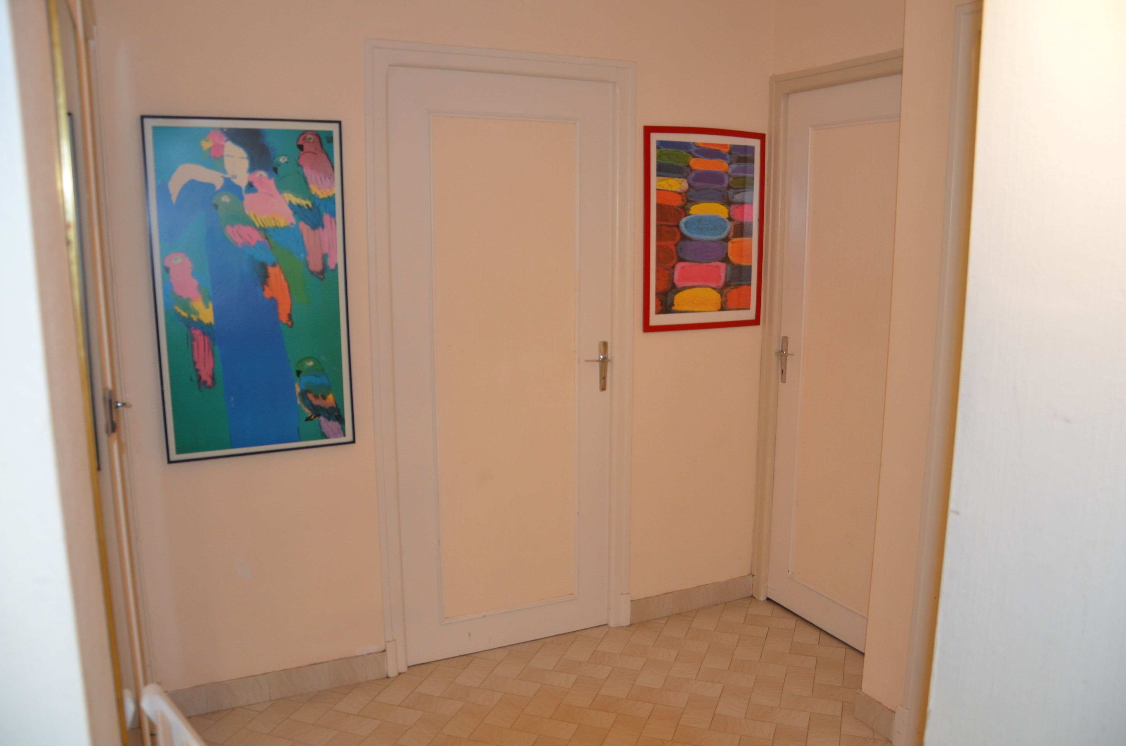 A hallway with two doors, one with a colorful abstract painting and another with a colorful geometric pattern.