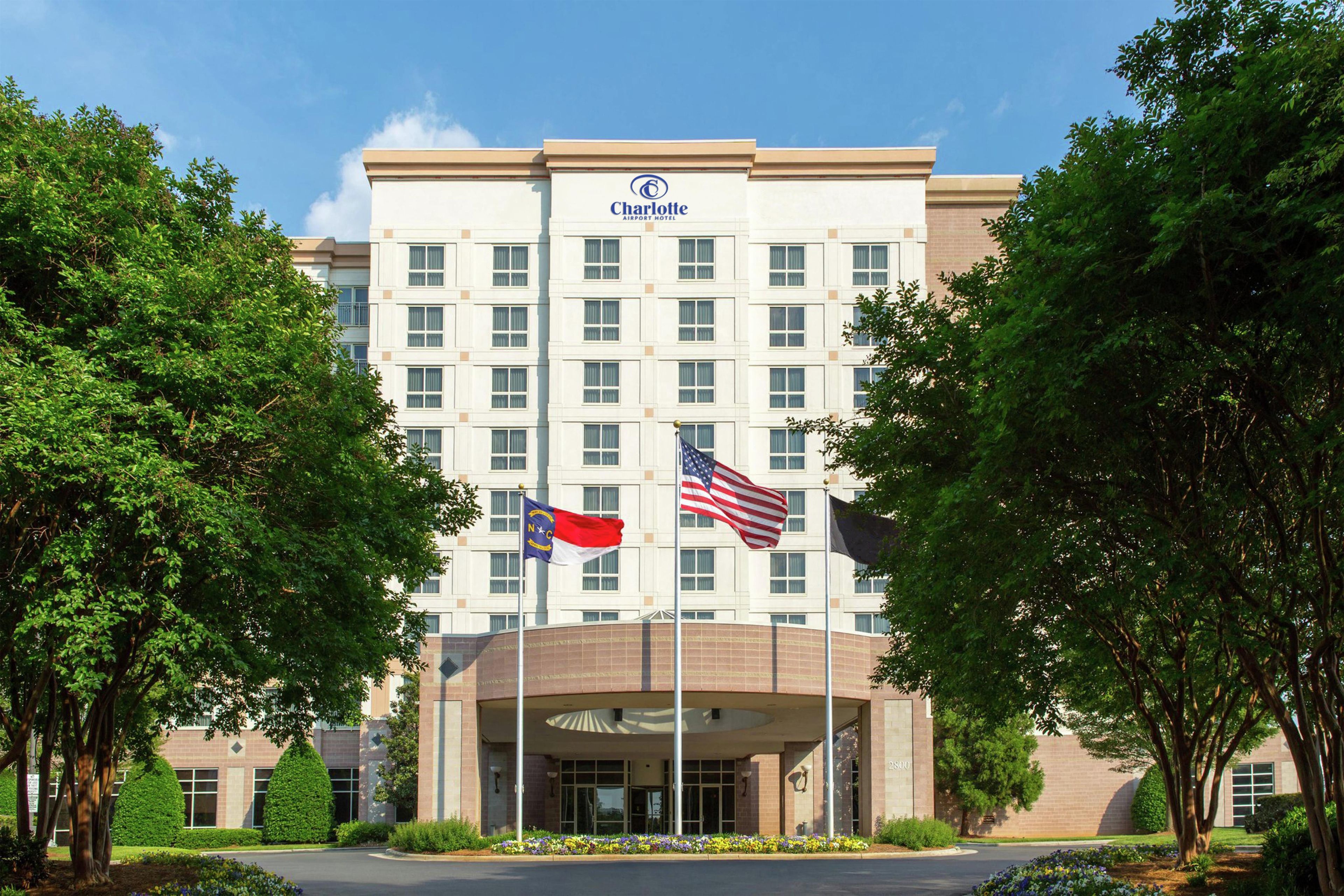 Un hotel cerca del Aeropuerto de Charlotte, con entrada central, pabellones con banderas y fachada simétrica.
