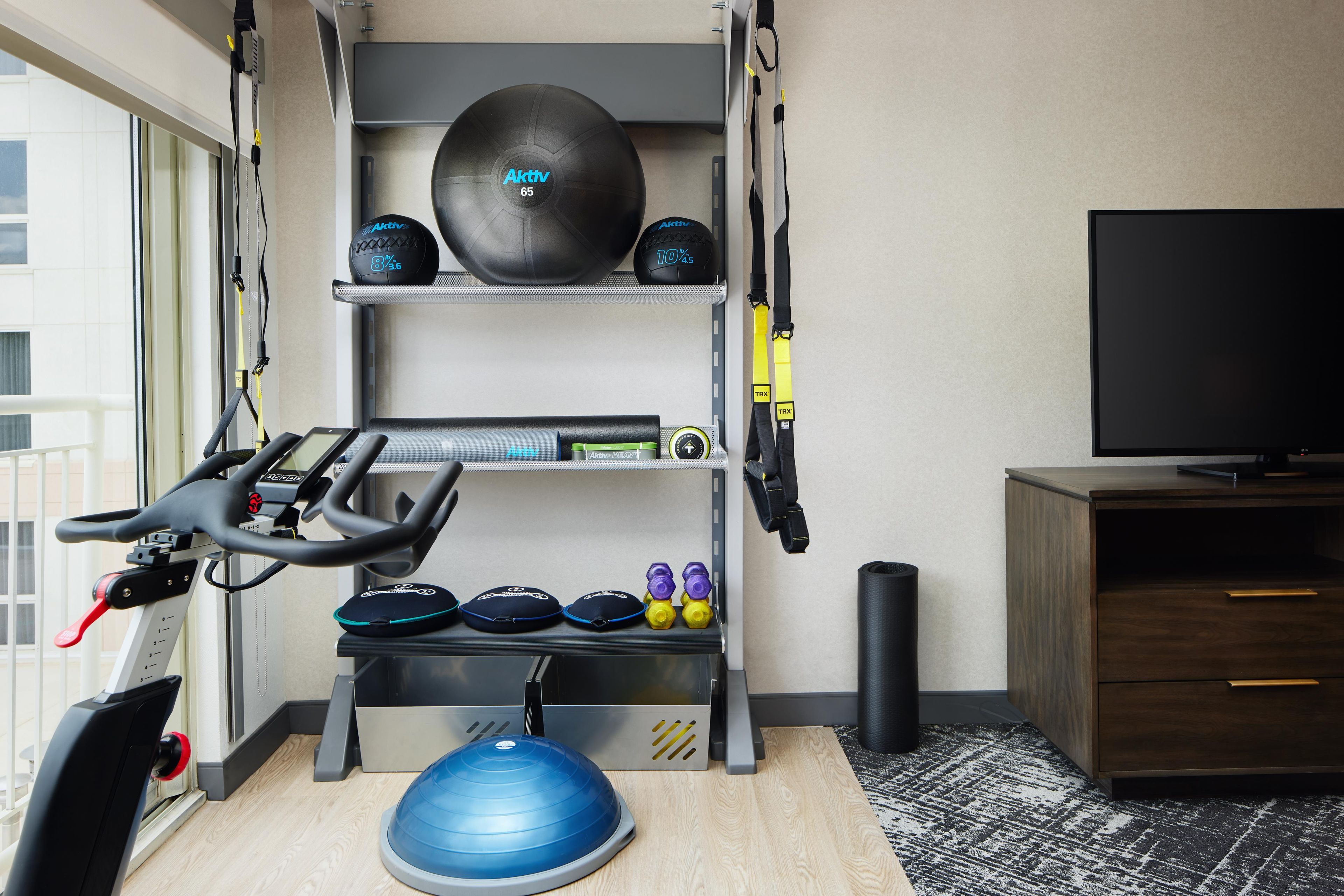 A home gym with a treadmill, exercise balls, dumbbells, and a blue stability ball.