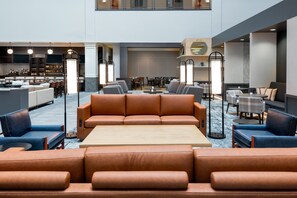 A spacious lobby with a central seating area, a bar, and a dining area.