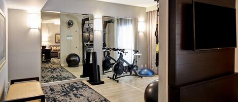 A hotel room with a treadmill, exercise ball, and a television.