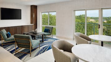 A modern living room with a flat-screen TV, a dining table, and two sofas.