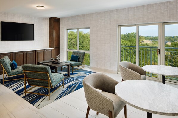 A modern living room with a flat-screen TV, a dining table, and two sofas.