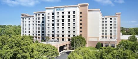 Un hotel de varios pisos con un llamativo letrero de 'Hilton', rodeado de exuberante follaje.