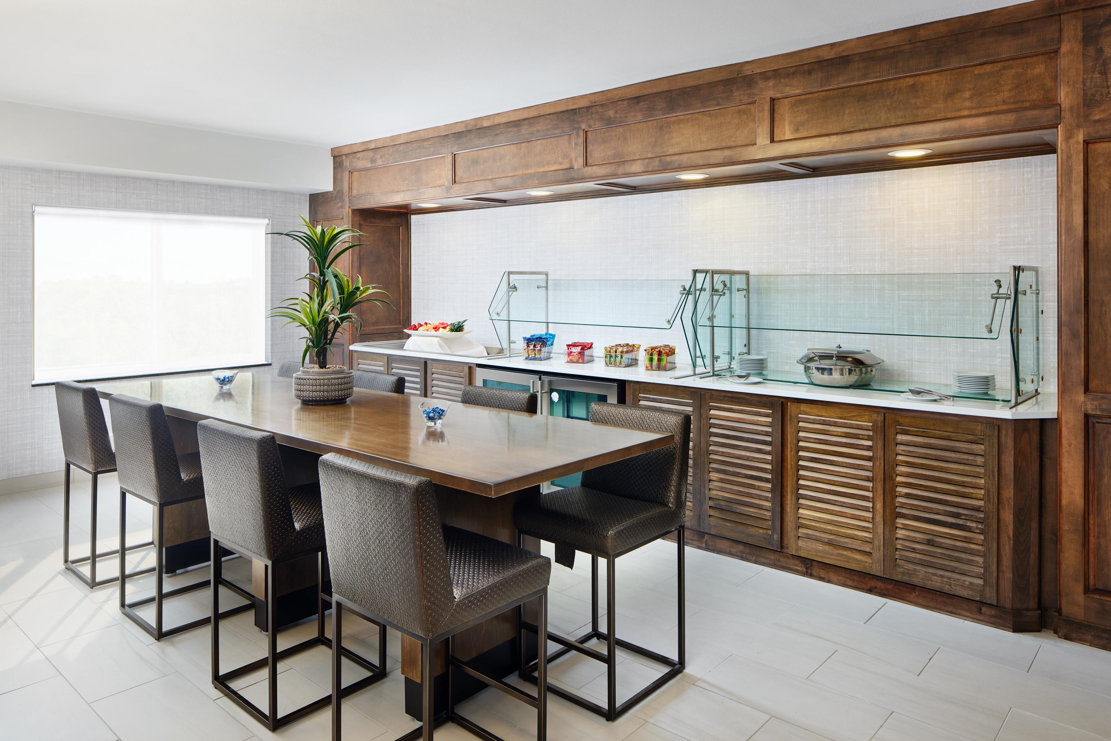 A modern kitchen with a wooden countertop, a glass display case, and a dining area with a large table and chairs.