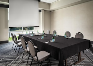 A conference room with a long table, chairs, a projector, and water bottles.