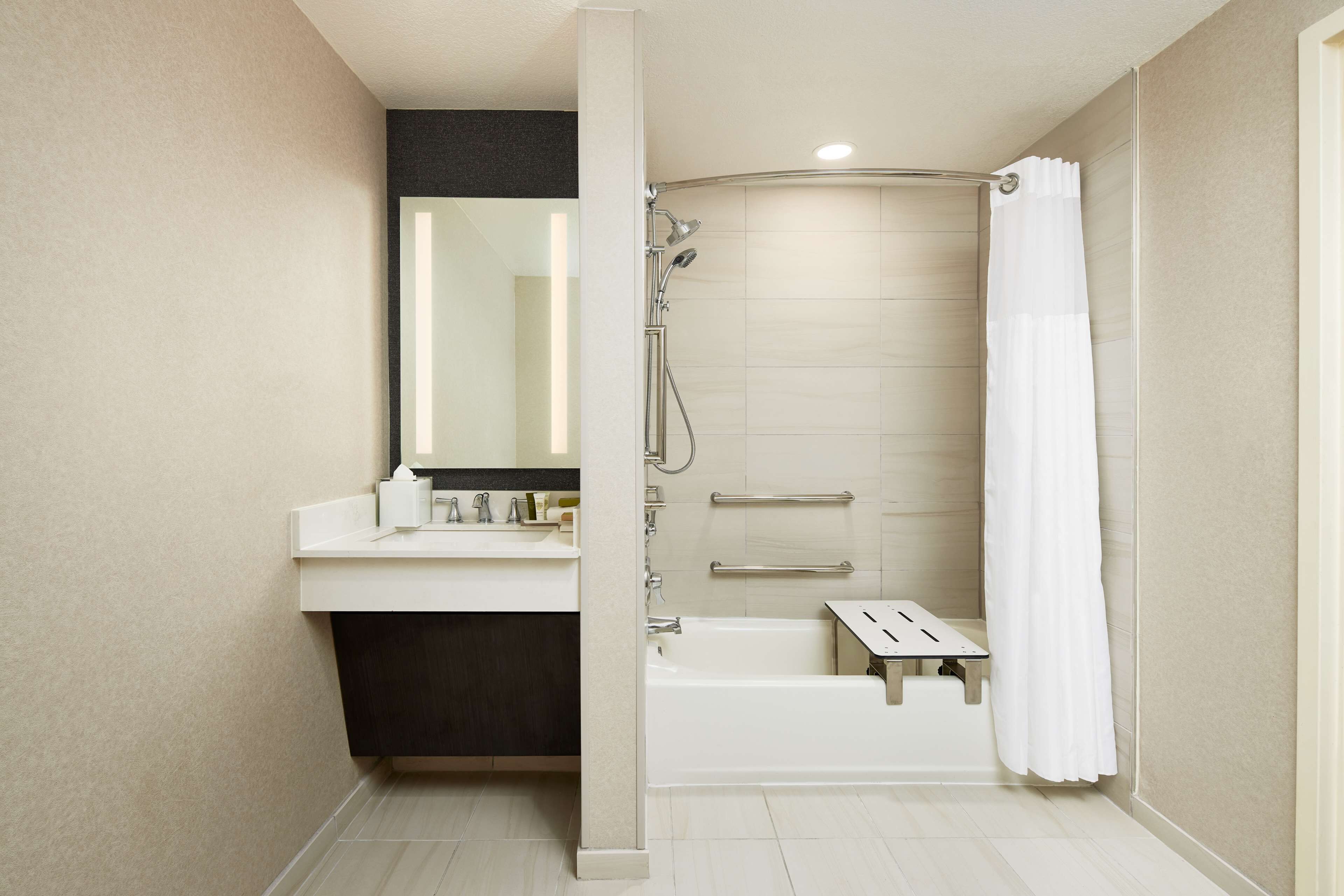 A modern bathroom with a bathtub, shower, and vanity.
