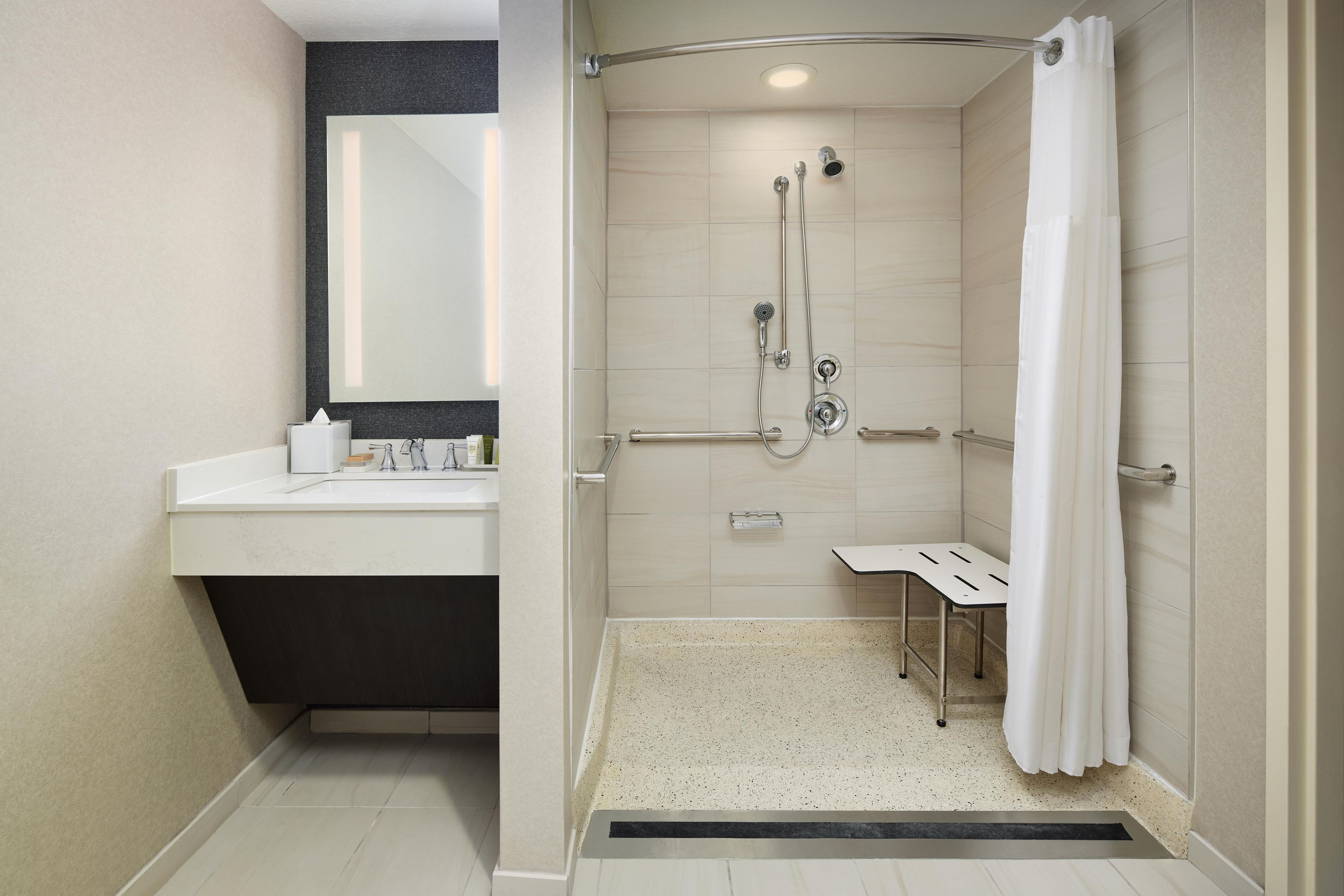 A modern bathroom with a shower, a sink, and a mirror.