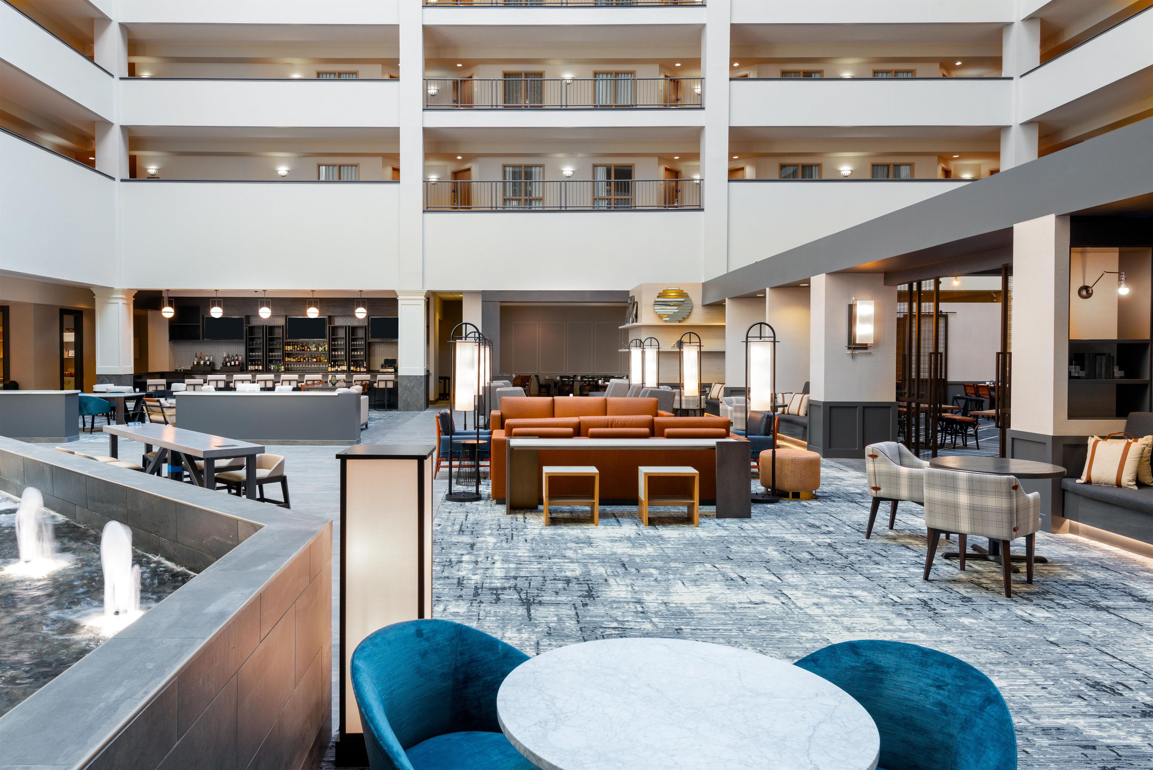 A spacious hotel lobby with a bar area, seating arrangements, and a decorative fountain.