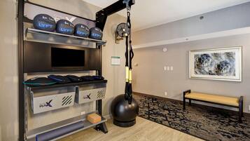 A gym with weightlifting equipment, a treadmill, and a bench.