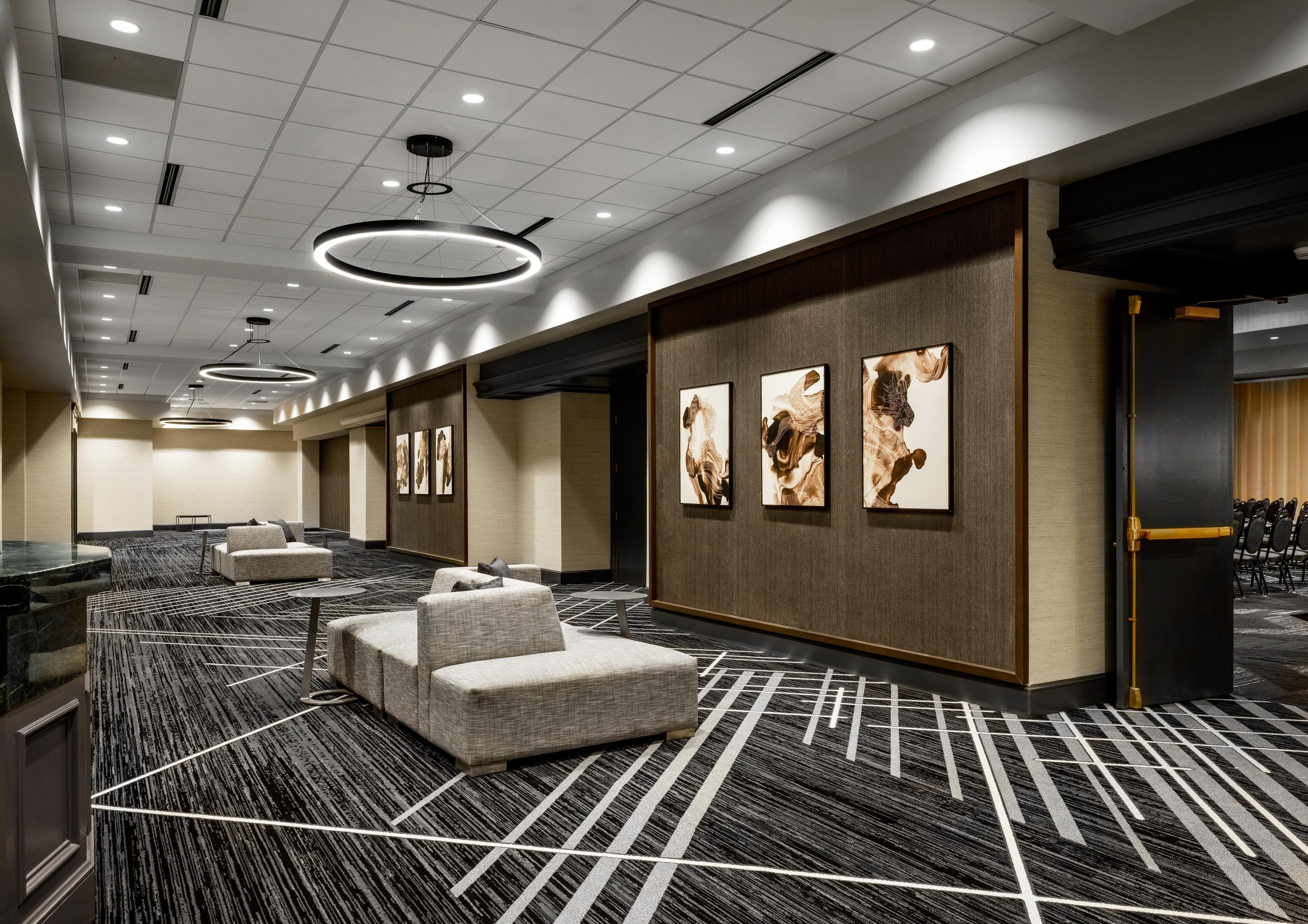 A hotel room with a large seating area, a reception desk, and artwork on the walls.
