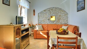 Una sala de estar acogedora con una pared de piedra, un aparador de madera y una mesa de comedor con fruta.