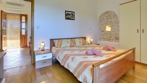 Un dormitorio con cama de madera, mesita de noche, armario y pared de piedra.