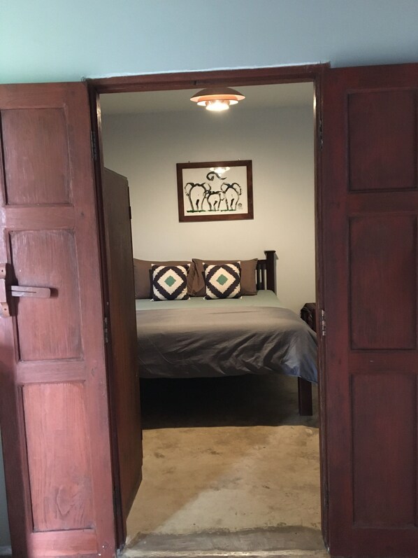 Un dormitorio con una cama, dos almohadas, una mesita de noche y un cuadro en la pared.