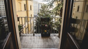 A balcony with potted plants and a view of surrounding buildings.