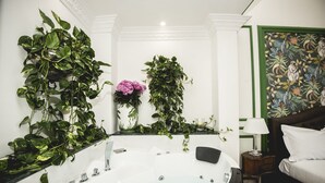 A bathroom with a large bathtub, a mirror, and several plants.