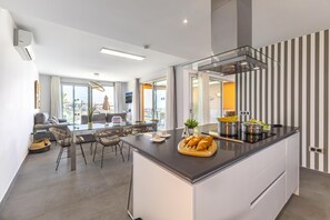 A modern kitchen with a central island, dining area with chairs, and a view to the outside.