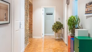 A hallway with wooden flooring, a stone wall, and a door leading to another room. - Al Garibaldino Rooms (Trieste)