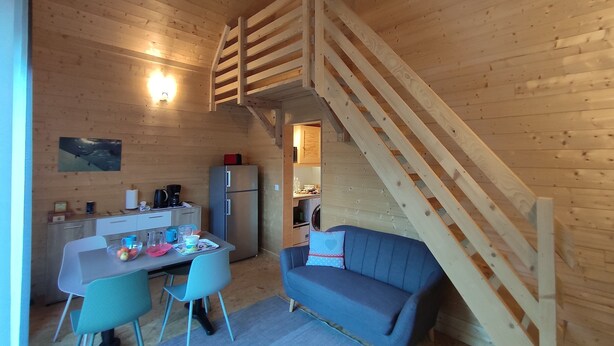 Interior acolhedor de uma cabana com sala de jantar, um sofá e uma escada.
