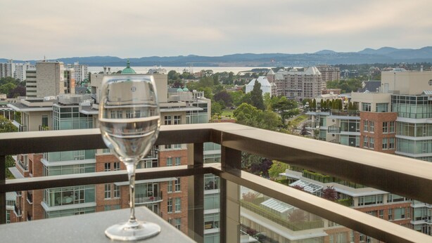Ein Balkon mit freiem Blick auf eine Stadtlandschaft, darunter Gebäude und ein Gewässer.