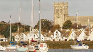 A coastal town with a prominent church tower, several white houses with steep roofs, and a marina with boats. - The Willows - Woodland Cottage with Log Burner (Christchurch)