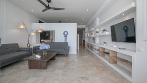 Un salon moderne avec un canapé gris, une table basse en bois et un téléviseur à écran plat fixé au mur.