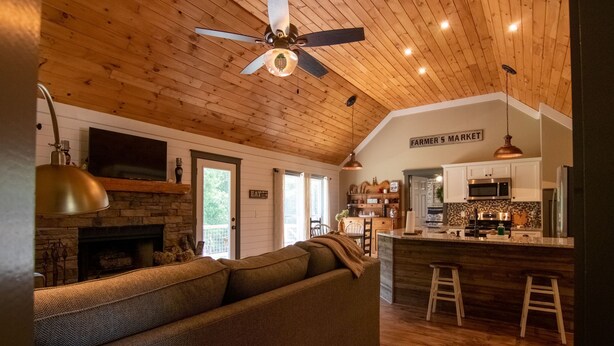 A cozy living room with a fireplace, a large sofa, and a kitchen area with a bar.