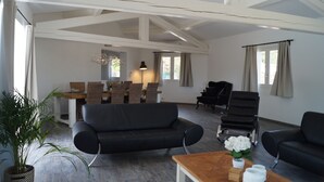 Un salón espacioso con techo alto, una mesa de comedor con sillas, un sofá y un piano.