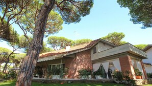 A two-story house with a brick facade, a tiled roof, and a covered porch with white curtains. - Villa Gio-Dì with large garden 300 meters from the sea (Marina di Grosseto)