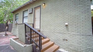 Ein eingeschossiges Haus mit Ziegelaußenwand, einer Haustür und einer kleinen Veranda mit Stufen.