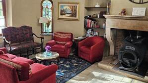 A cozy living room with red sofas, a fireplace, a large clock, and a stained glass window. - Character cottage near Verdun (Dieue-sur-Meuse)