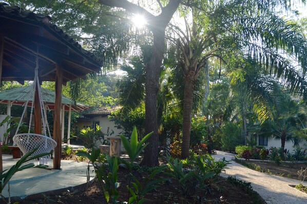 A garden with a swing, palm trees, and a gazebo.