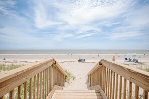 A wooden staircase leading to a beach with a clear sky.