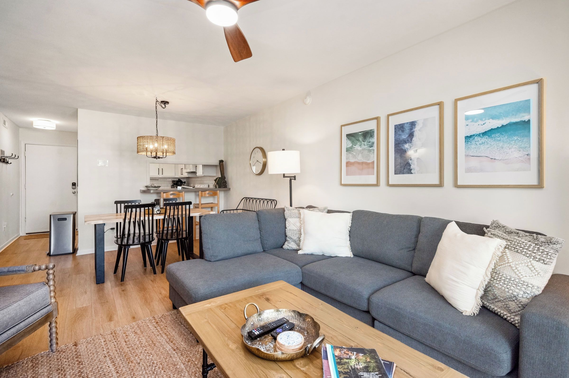 En moderne stue med en grå sofa, et træsofabord og et spiseområde med stole og bord.