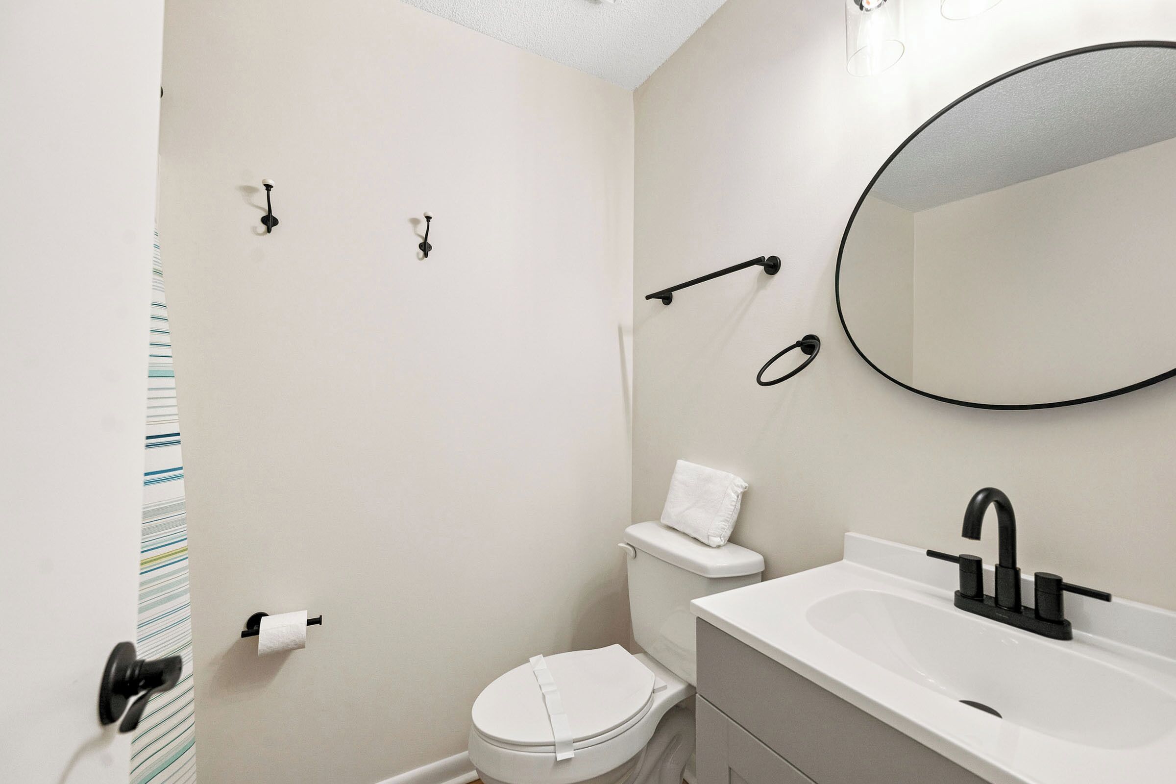 A bathroom with a toilet, sink, and mirror.