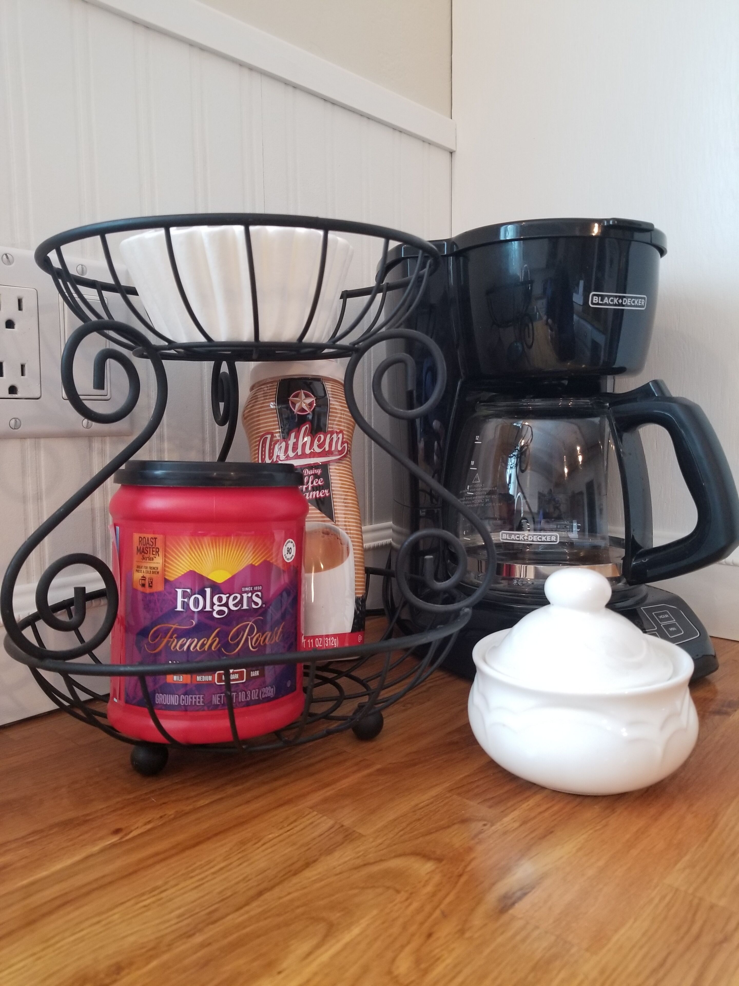 Una encimera de cocina con café Folgers French Roast, un tarro de mantequilla y una cafetera Black+Decker.