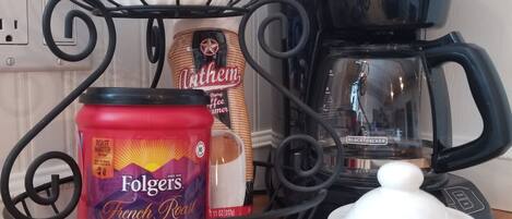 Una encimera de cocina con café Folgers French Roast, un tarro de mantequilla y una cafetera Black+Decker.