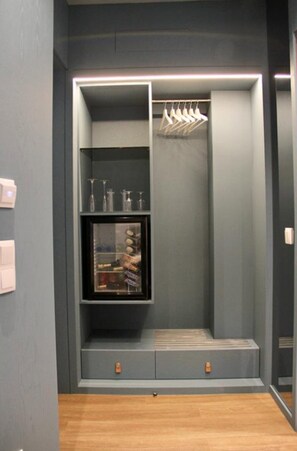 Um guarda-roupa moderno com prateleiras embutidas, cabideiro e uma vitrine de vidro.