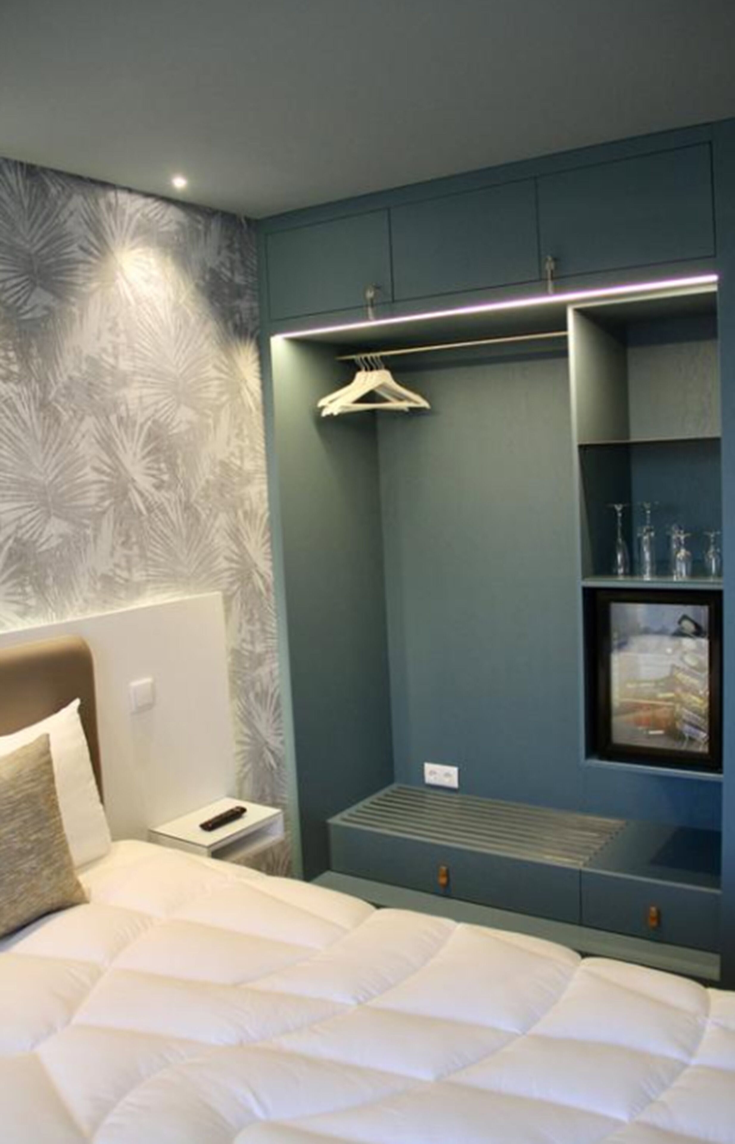 Un dormitorio con cama, mesita de noche, armario y una estantería con adornos.