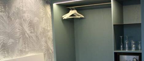 Un dormitorio con cama, mesita de noche, armario y una estantería con adornos.