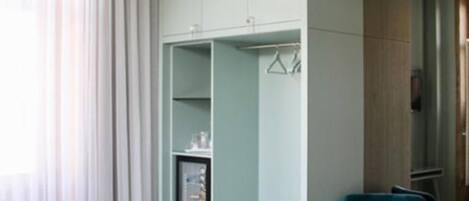 A modern hotel room with a bed, a wardrobe, and a seating area.