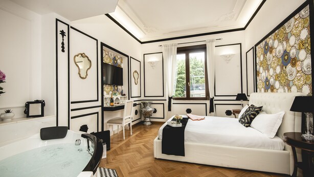 A bedroom with a large bed, a vanity with a mirror, a bathtub, and a wall with decorative plates. - TS. Peter's Fashion suite with jacuzzi Vaticano-Rome (roma)