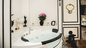 A modern bathroom with a large bathtub, a vanity with a mirror, and a decorative vase with flowers. - TS. Peter's Fashion suite with jacuzzi Vaticano-Rome (roma)