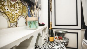 A bar area with a bottle of champagne, glasses, and a fruit basket on a patterned table. - TS. Peter's Fashion suite with jacuzzi Vaticano-Rome (roma)