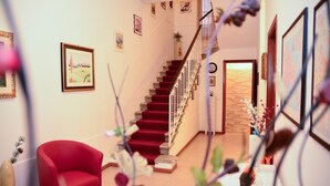 Un escalier recouvert d’une moquette rouge mène à une porte en bois.