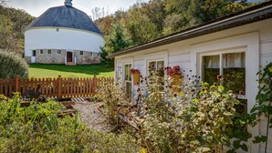 A white building with a stone foundation and a wooden fence. - Round Barn Farm B & B Event Center (Red Wing)