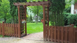 A wooden arbor with hanging flower pots and a brick pathway leading to a gazebo. - Round Barn Farm B & B Event Center (Red Wing)