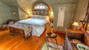 A cozy bedroom with a large bed, wooden furniture, and patterned wallpaper. - Round Barn Farm B & B Event Center (Red Wing)