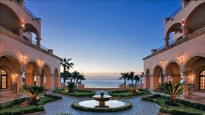 A courtyard with a central fountain, surrounded by palm trees and a view of the ocean. - Sheraton Hacienda Del Mar Easter Week 4/6/-4/13 (Hacienda del Mar Cabo San Lucas)