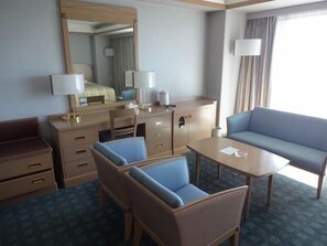 Una habitación de hotel con cama, escritorio, silla, sofá y una mesita.
